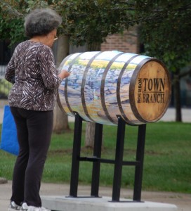 A person looks at the artwork on a barrel in downtown Lexington