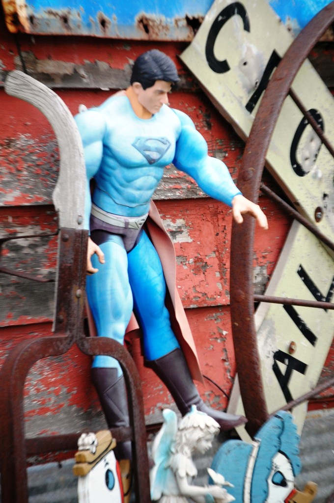 Superman is hung forever on the side of Boudreau's antiques...saving a little doll?