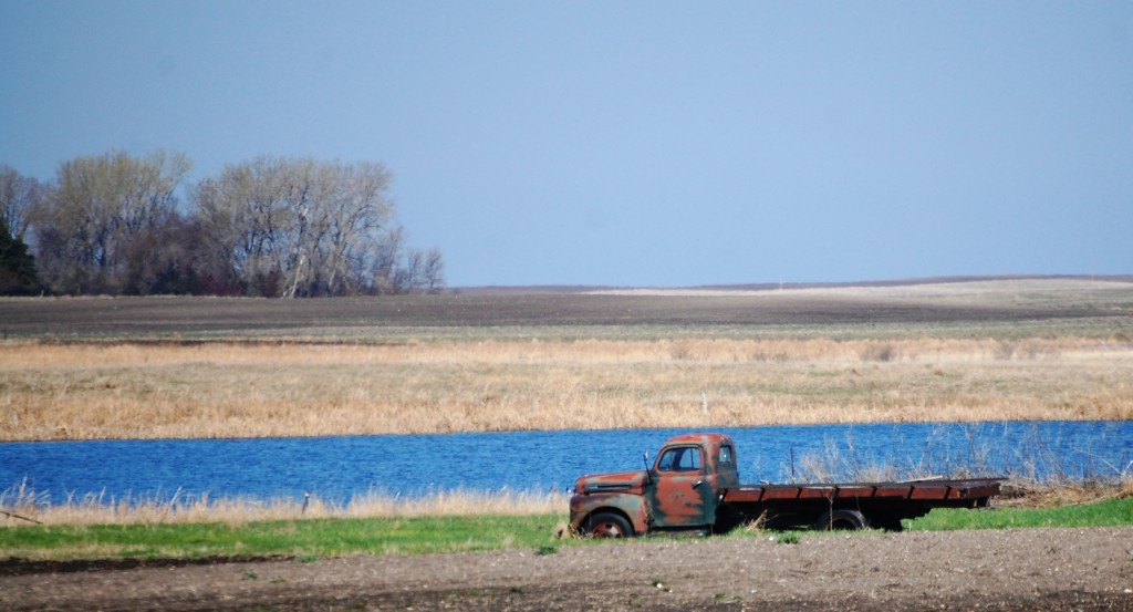 An old truck rests by one of the many ponds along ND Highway 1