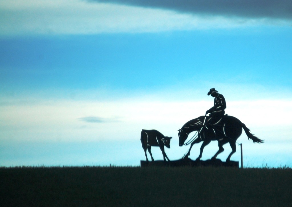 A metal cowboy sculpture on a hill south of Choteau, Montana is silhouetted against the morning sky. 