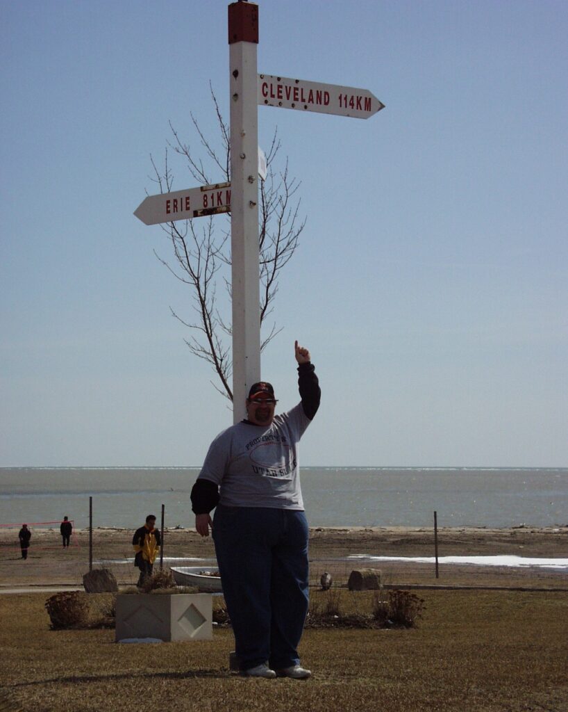 At Lake Erie on the Ontario, Canada side with sign pointing to Cleveland, OH, my birthplace