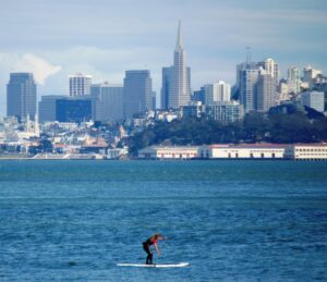 A paddle boarder in the bay with the city behind her