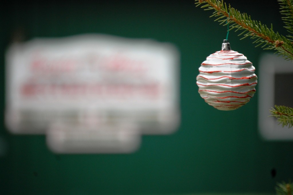 An ornament adorns a branch on a tree in front of the Santa Claus Museum