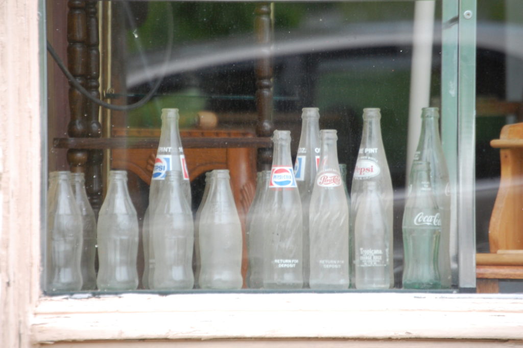 A collection of old soda bottles sits in a window of a store front in Ravenna