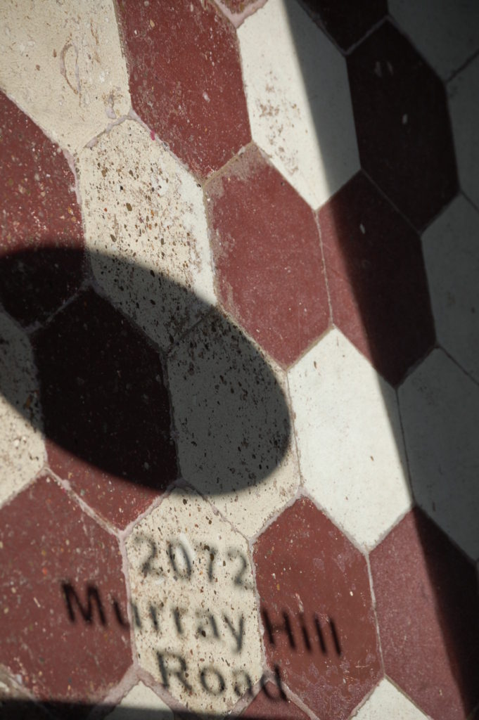 Reflection of address on old tile floor of Murray Hill Hill Market